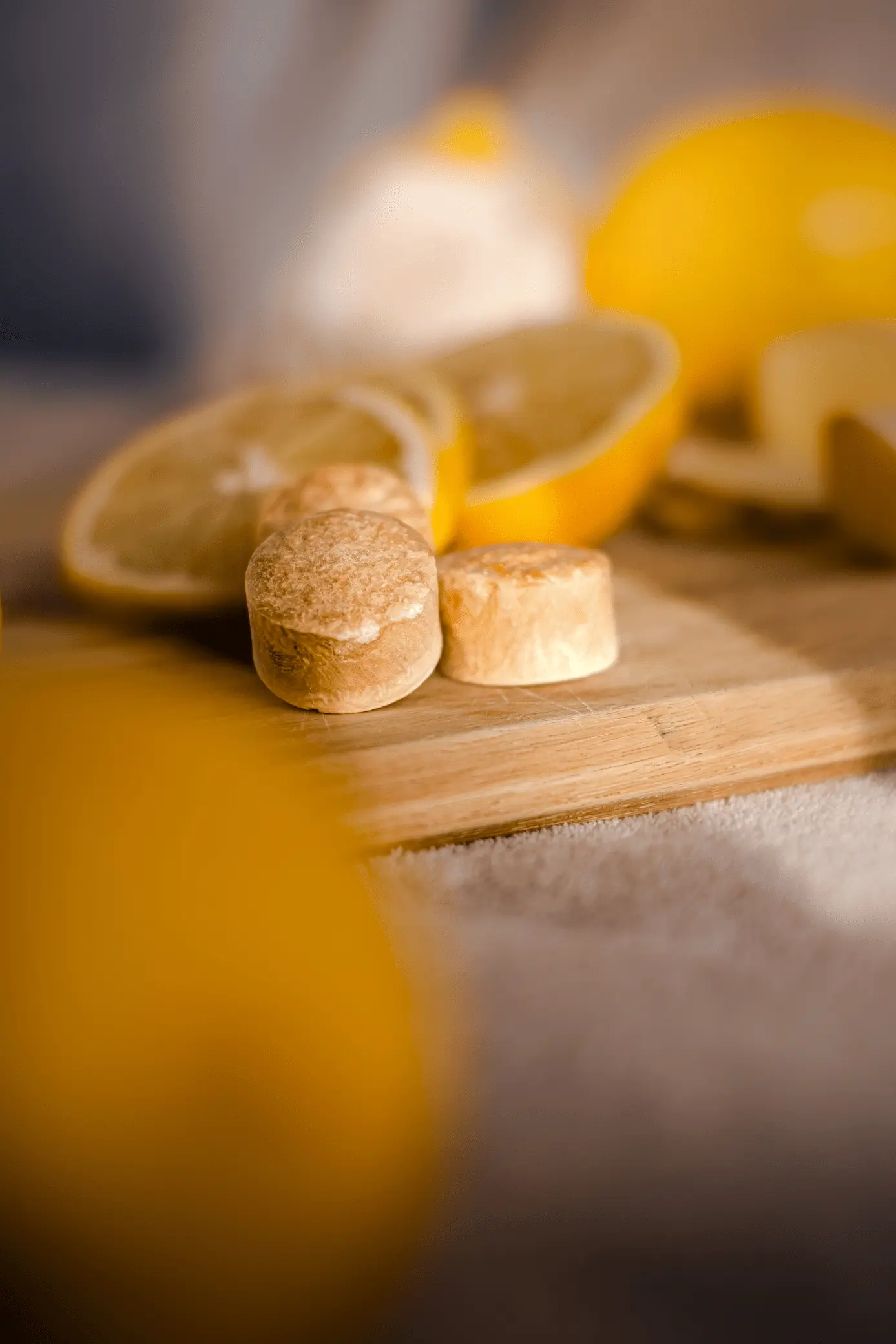 Pastilles de thé Instan’T saveur citron avec tranches de citron sur planche en bois.